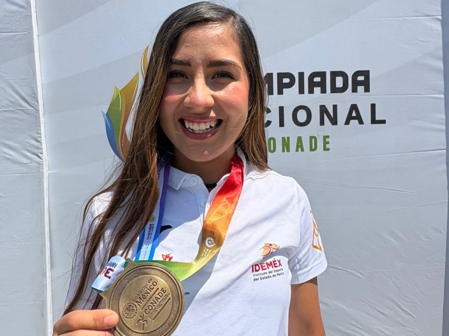 Joven sonriente sosteniendo una medalla de bronce, con un collar de medallas y un fondo que dice 'Olimpiada Nacional'.