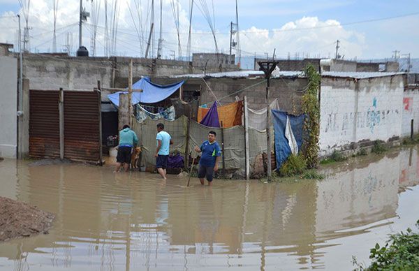 Hombres trabajando en una zona inundada, rodeados de agua y estructuras precarias.
