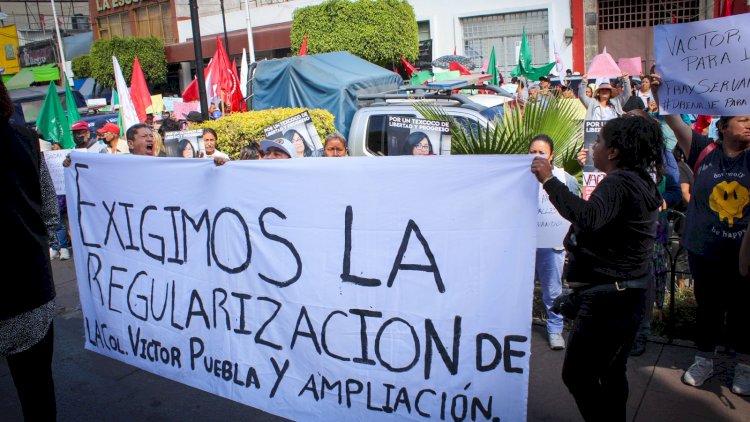 Manifestantes sosteniendo una pancarta que dice 'Exigimos la regularización de la Col. Victor Puebla y ampliación' durante una protesta en la calle.