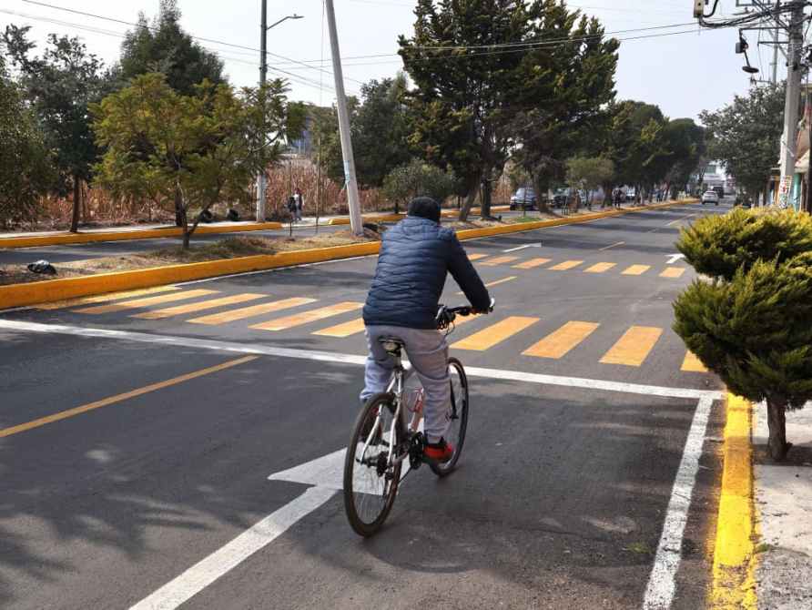 Un ciclista montando una bicicleta en una calle con líneas de cruce peatonal amarillas.