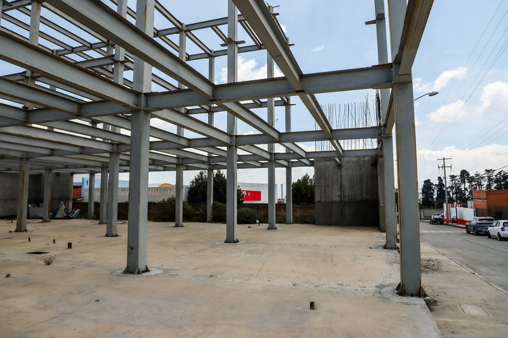Estructura de un edificio en construcción con columnas de acero y un área despejada en el suelo.