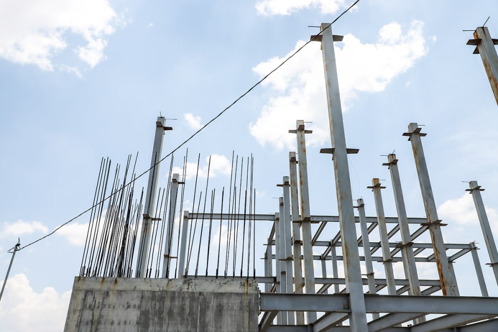 Estructura de construcción con varillas de acero y cielo azul con nubes.