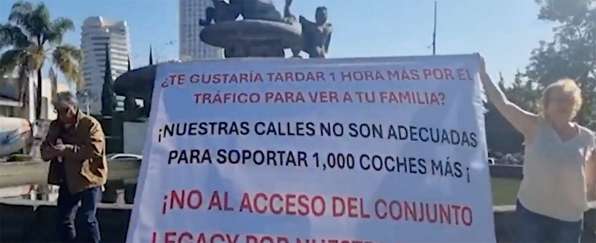 Manifestación en la calle con un cartel que denuncia el tráfico y la falta de infraestructura vial adecuada.