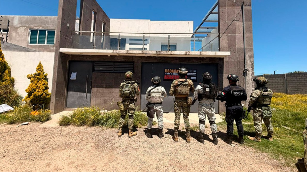 Grupo de agentes de seguridad uniformados de pie frente a un edificio con un letrero que dice 'FISCALÍA ESTADO DE MÉXICO'.