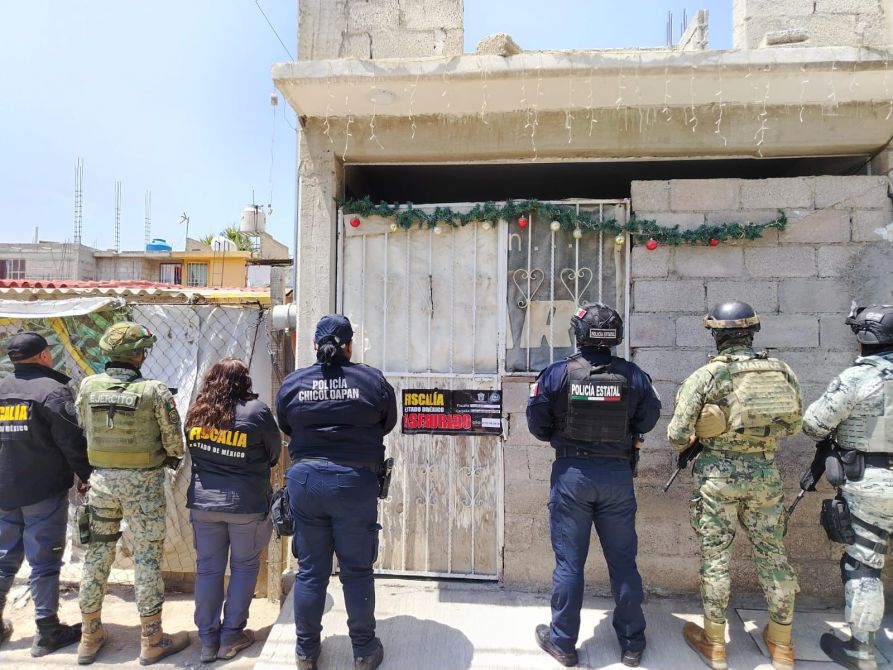 Un grupo de oficiales de la policía y el ejército frente a una puerta cerrada con un letrero de 'clausurado'.