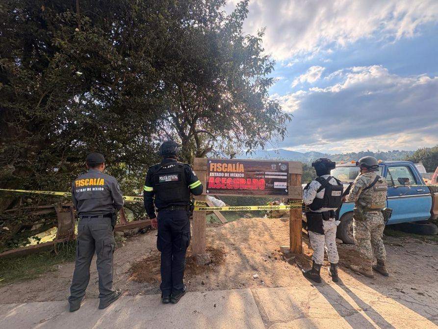Agentes de la Fiscalía y policía estatal frente a un letrero que indica zona asegurada, con cintas de prohibido pasar.