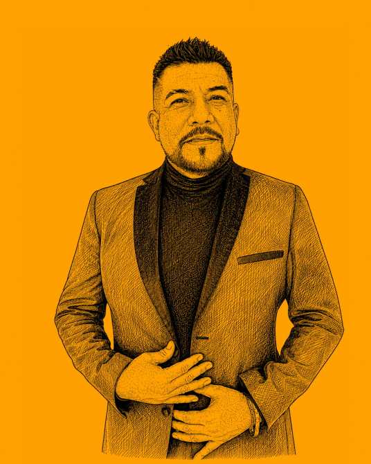 Retrato de un hombre con chaqueta y camiseta negra, en un fondo naranja. Él tiene una expresión seria y está de pie, con las manos en su cintura.