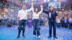 Fernando Flores, alcalde de Metepec, aparece junto a su esposa Iraí Albarrán y el senador Enrique Vargas durante un evento masivo del PAN. Los tres levantan las manos sobre un escenario mientras cae confeti azul y blanco frente a cientos de simpatizantes.
