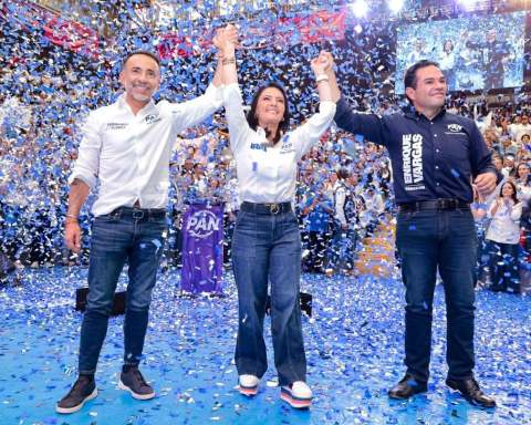Fernando Flores, alcalde de Metepec, aparece junto a su esposa Iraí Albarrán y el senador Enrique Vargas durante un evento masivo del PAN. Los tres levantan las manos sobre un escenario mientras cae confeti azul y blanco frente a cientos de simpatizantes.