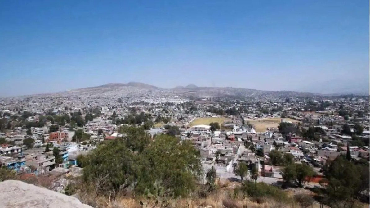 Vista panorámica de una ciudad con numerosos edificios residenciales y terrenos abiertos, bajo un cielo despejado.