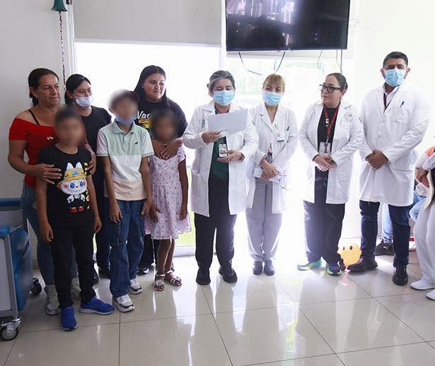 Grupo de personas en un hospital, incluyendo médicos y pacientes, en un ambiente acogedor, todos usando mascarillas.